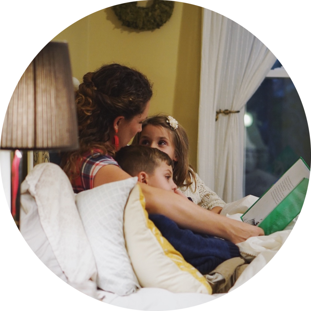 Parent and 2 children reading in bed.
